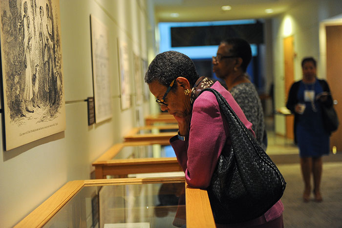 A woman looks at an item on display at the "Framing Shadows" exhibit