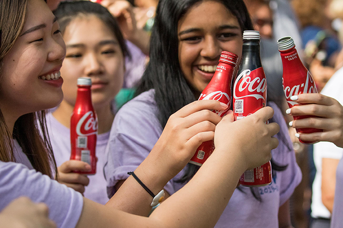 Students hold bottles of Coke high for the Coke Toast