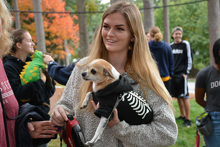 A young woman holds a small dog in a skeleton costume
