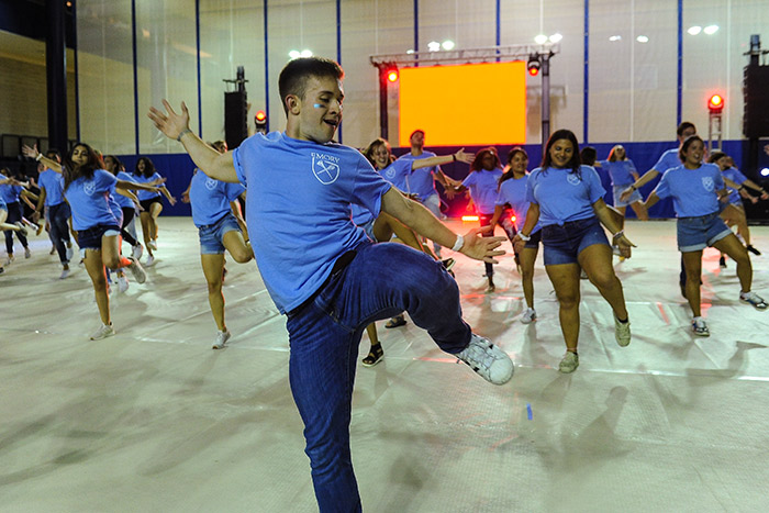 Students in blue t-shirts dance at Songfest