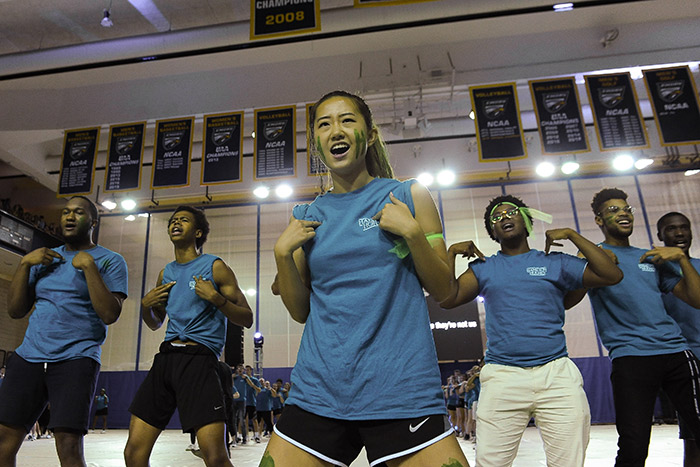 Students in blue t-shirts dance and sing