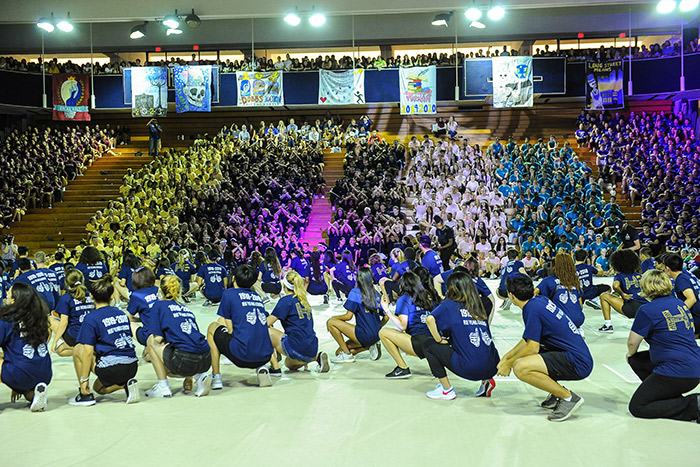Students in blue t-shirts squat in sync at Songfest