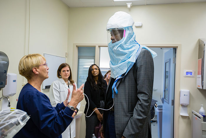 Dikembe Mutombo tries on a powered air-purifying respirator, which looks like a large blue hood with a clear plastic mask to look out through