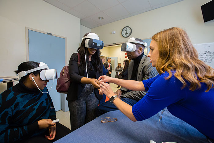 Dikembe Mutombo and others wear virtual reality headsets to view how health care workers care for Ebola patients