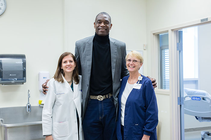 Dikembe Mutombo poses with Emory infectious disease physician Colleen Kraft (left) and critical care nurse Jill Morgan (right) during a visit to the Serious Communicable Diseases Unit.