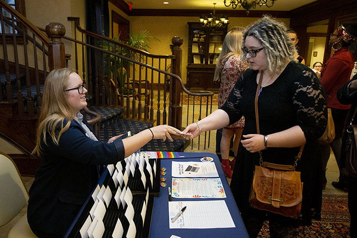 A woman hands another woman her name tag at a table at the Pride Awards