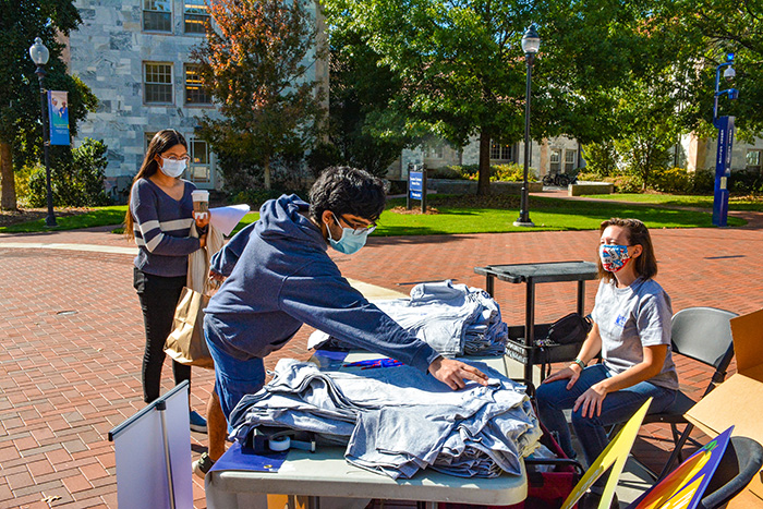 Students in masks give out t-shirts on the quadrangle