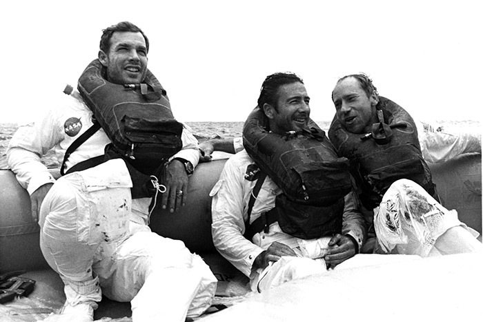The Apollo 15 crew smile in the lifeboat awaiting helicopter pickup after splashdown