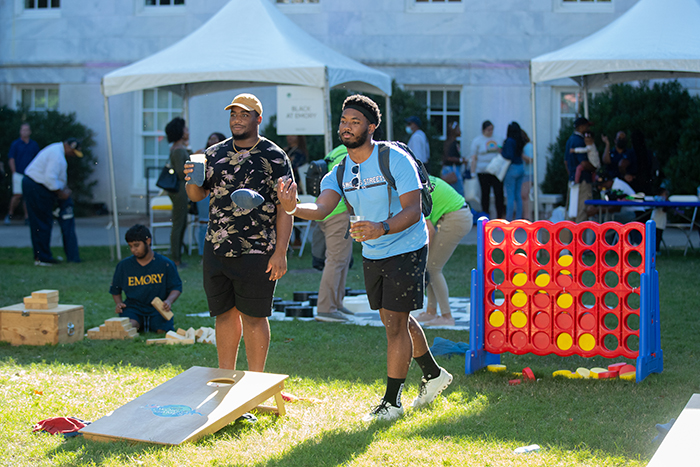 Two students play corn hole on the quad