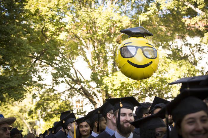 a smiley-face baloon floats above the seated crowd of graduates