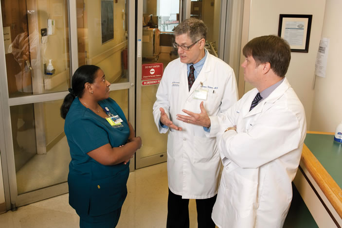 Isolation unit nursing director Carolyn Hill, medical director Bruce Ribner, and pathologist Charles Hill (far right) confer just outside the doors to Emory University Hospital's Serious Communicable Disease Unit.