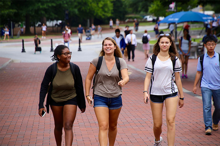 three women walking on campus