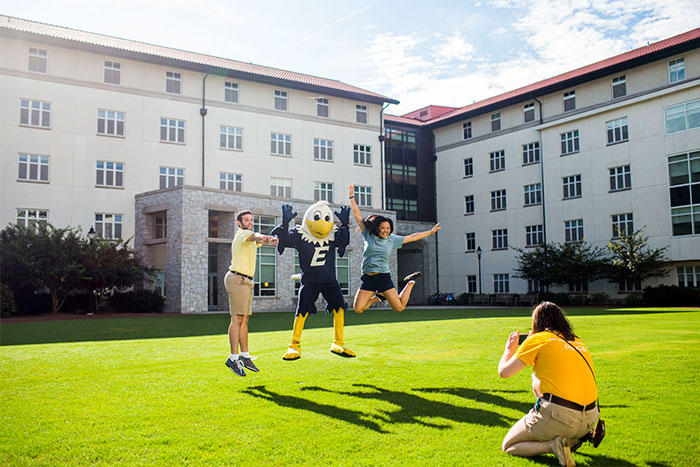swoop mascot jumping with two people