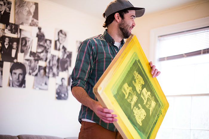 Rory Hawkins, the artist behind Catlanta, holds the print screen of the Dooley cats in his East Atlanta house.