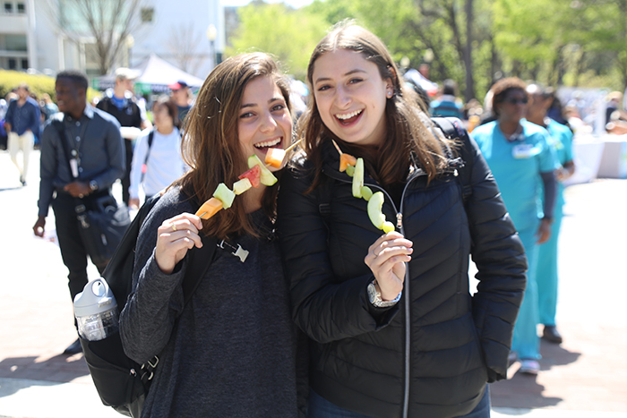 two females eating fruit kabobs