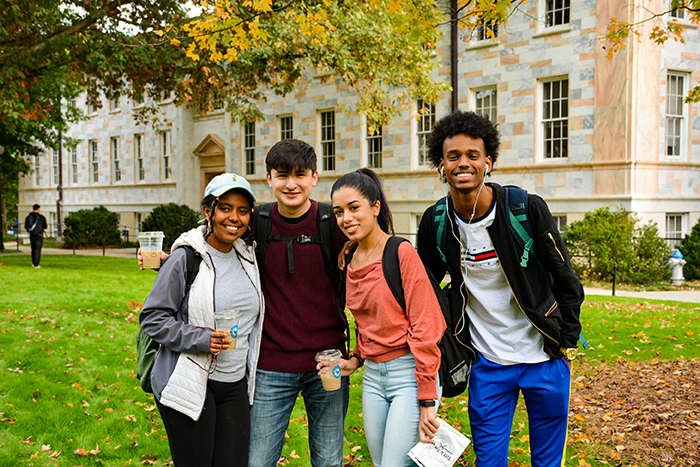 Four students pose on the quad