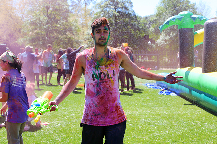 Male with water gun covered in diffirent colors