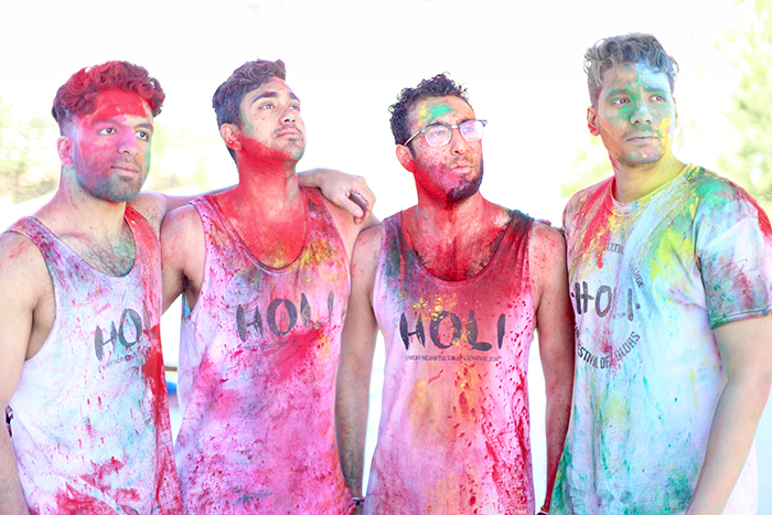 four males posing with colored powder all over them