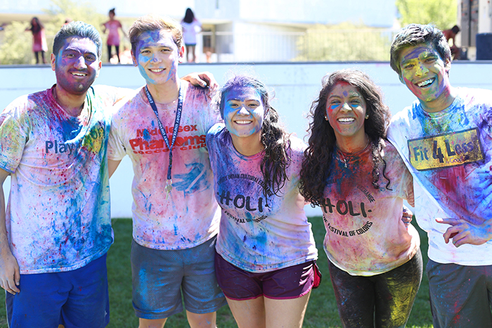 four students covered in colored powder pose