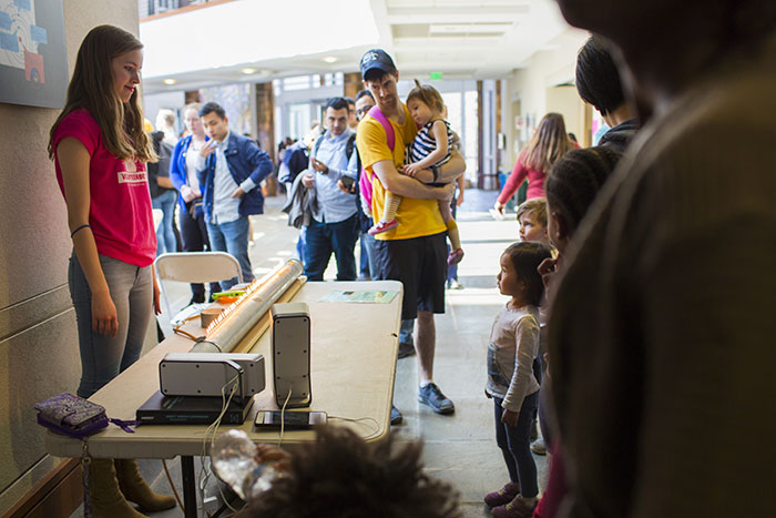 A toddler and a student demonstrator make eye contact during a demonstration at the Chemistry Carnival