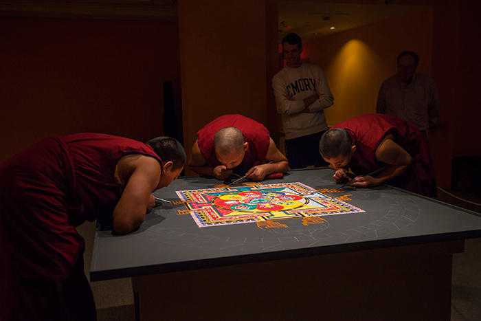 Three monks creating mandala