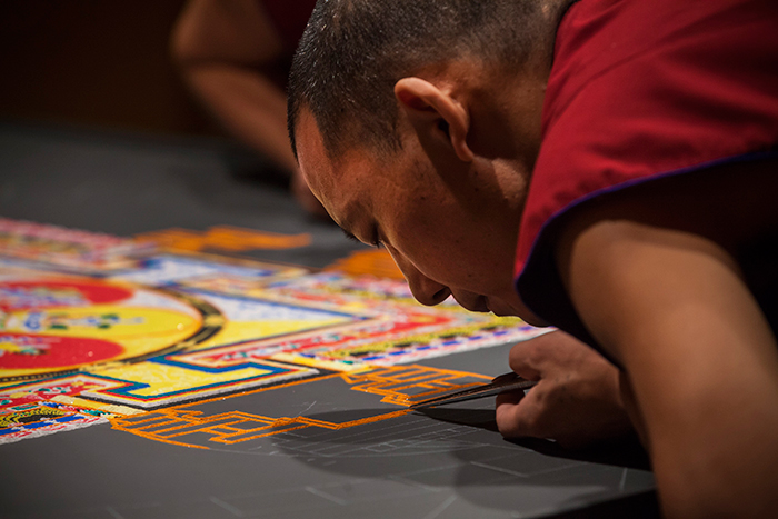 Close up of tibetan monk working on mandala