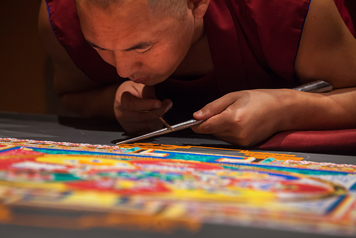 Close up of tibetan monk working on mandala