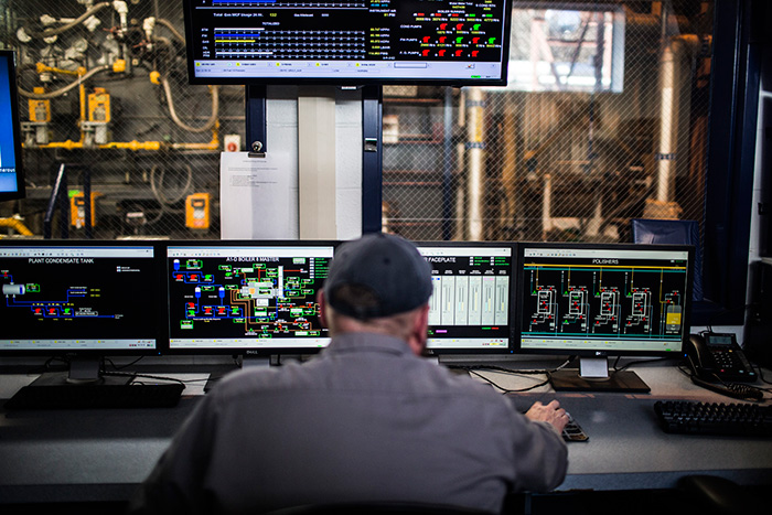 Man sitting at control panel inside steam plant
