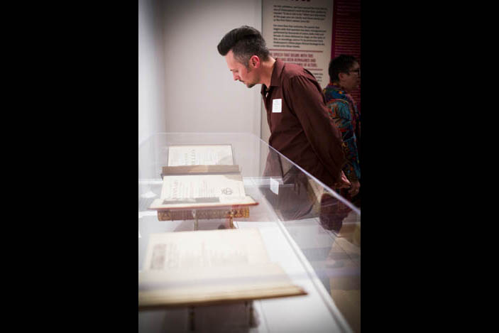 A man studies an exhibit containing the second, third and fourth folios.