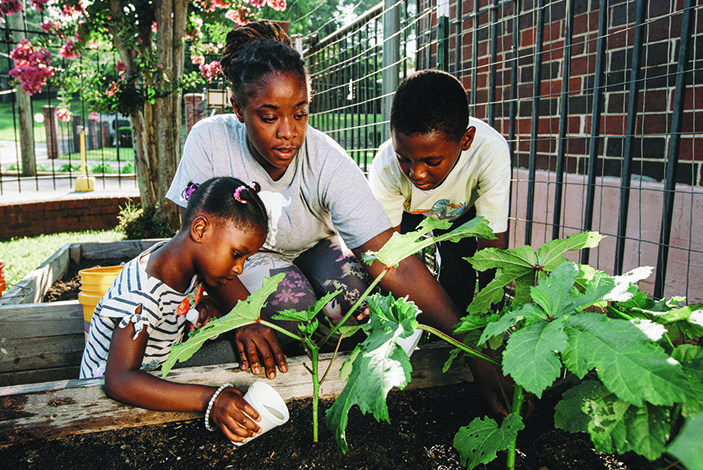 Rayonna Thompson works with her daughter, Bella, and son, Ben, in her garden plot outside her apartment in Atlanta's Westside.  The garden is part of a project that received a HERCULES community grant. 