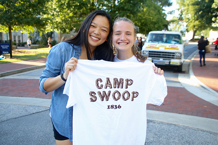Two female students holding up Camp Swoop t-shirt.