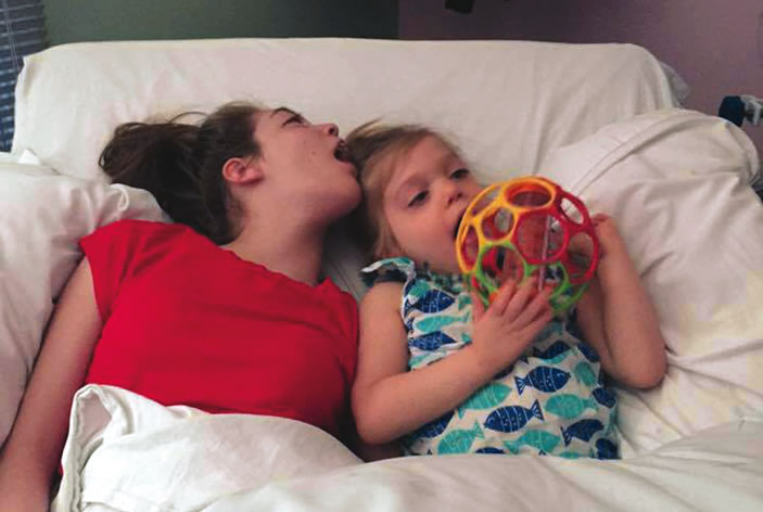 Sisters Jordan and Jessie, who share the same rare genetic condition, snuggle in bed