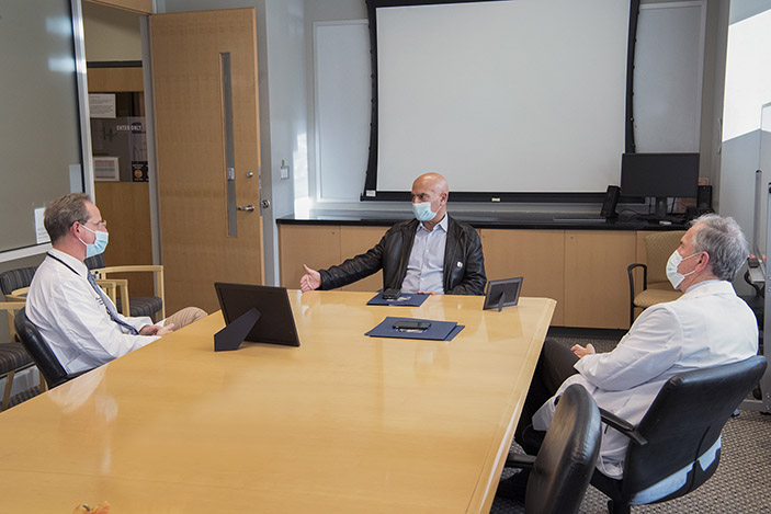 Moncef Slaoui speaks to Evan Anderson about the status Operation Warp Speed in a conference room at the Emory Children’s Center. David S. Stephens looks on.