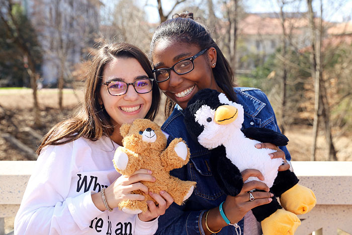 Two female students pose with their toy animals.