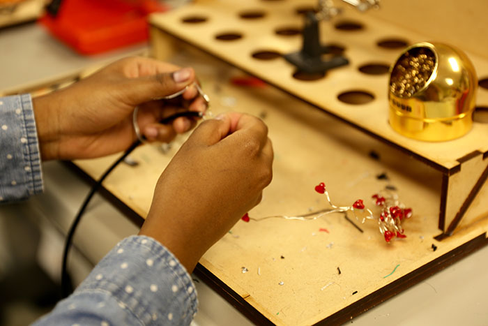 A student solders a string of tiny Valentine's Day lights.