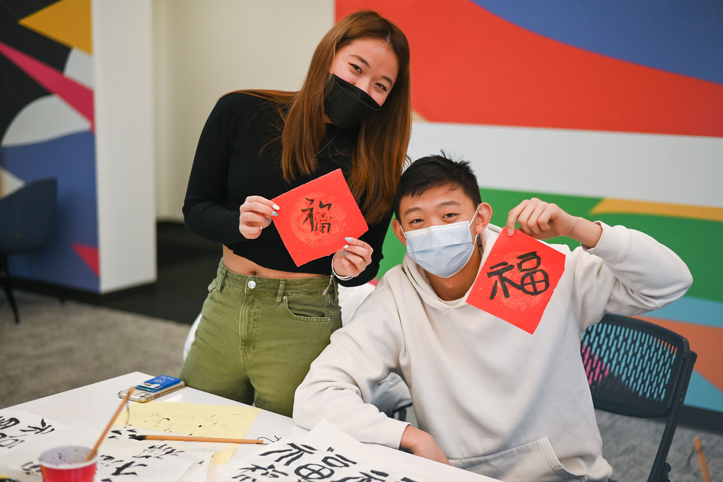 Two young people hold up their calligraphy projects