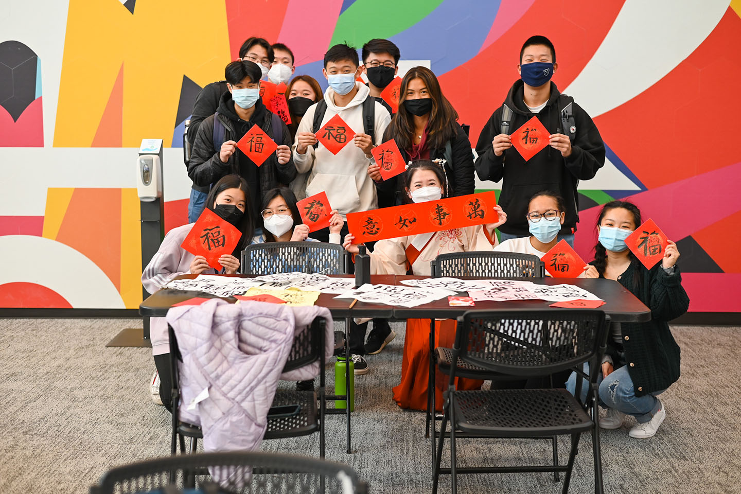 A group of students hold up their calligraphy projects