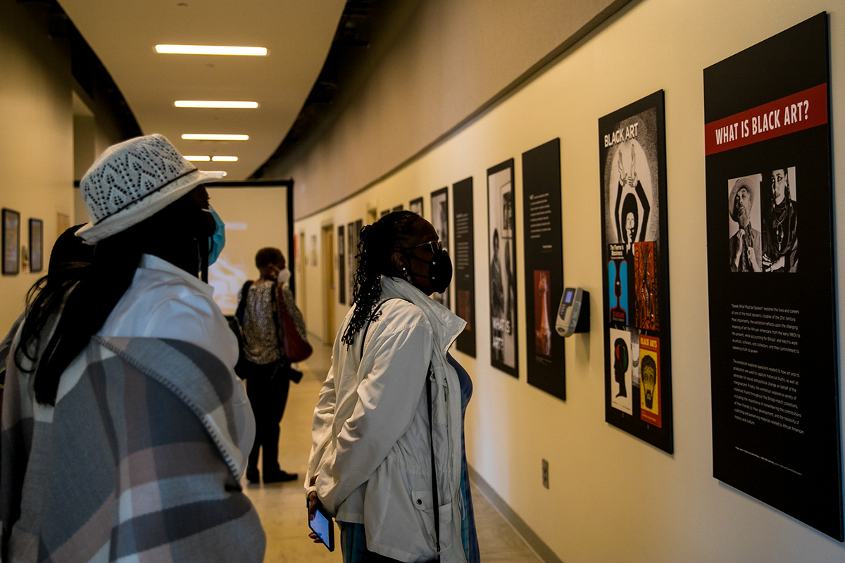 Community members look at art hanging in a hallway