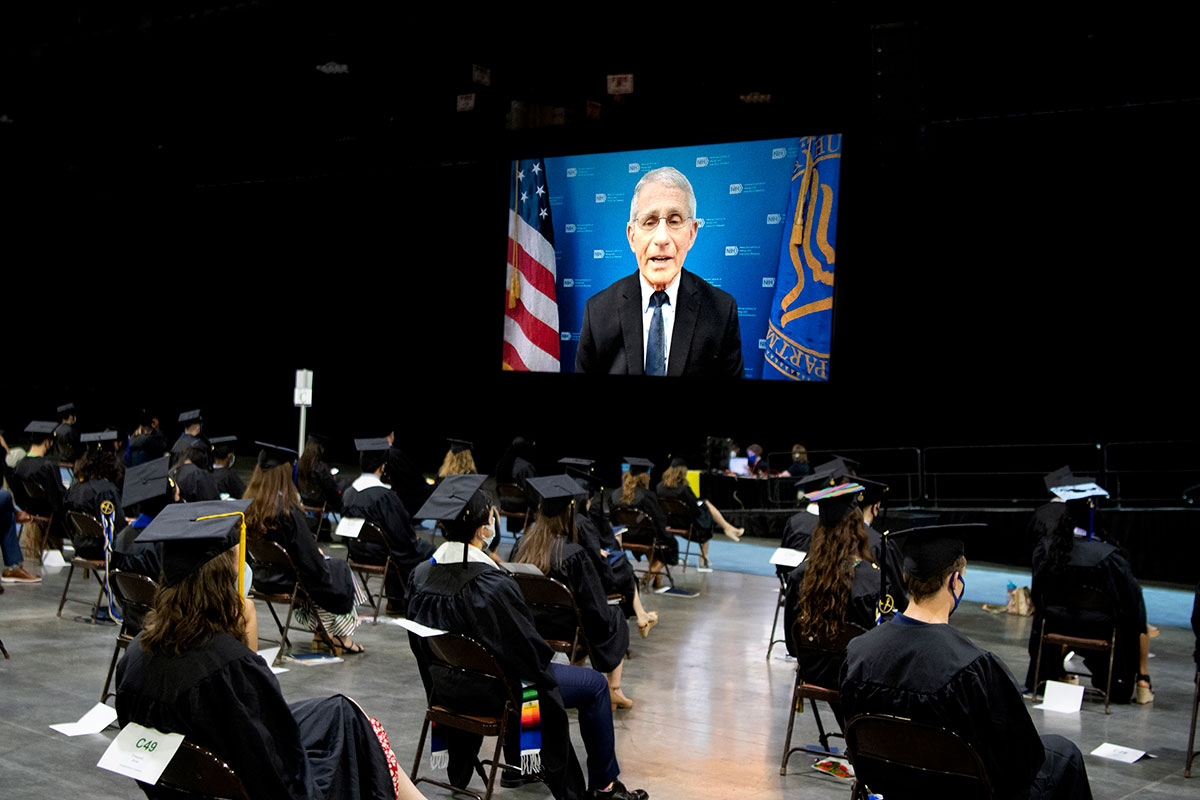 Anthony Fauci on a screen with Emory graduates in chairs