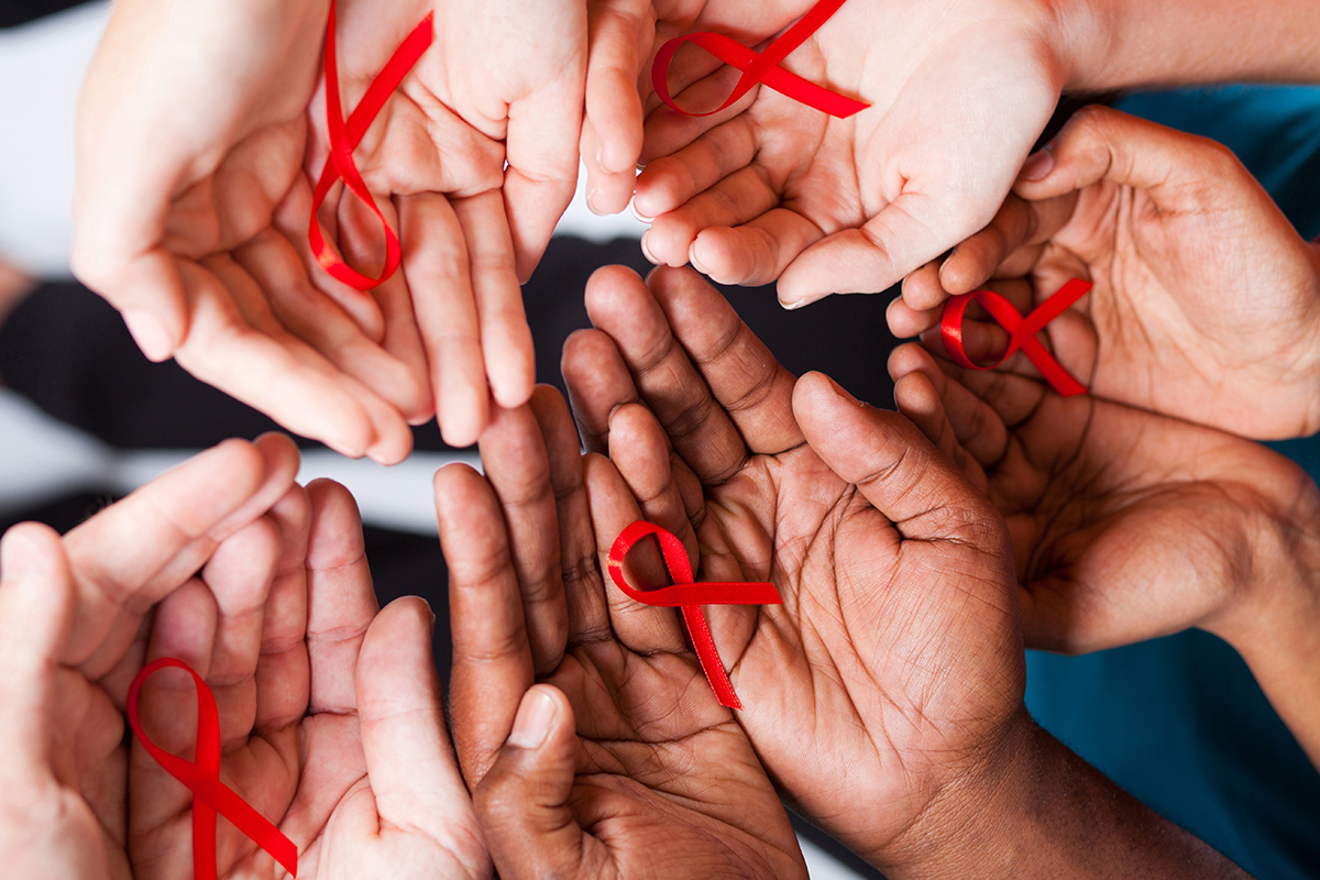 people holding red ribbons for HIV awareness in their hands